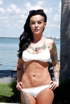 Tattooed whore Lolo Luscious exposing big hooters in swimming pool on www.girlzfan.com